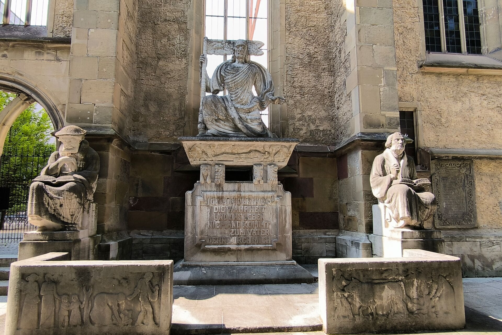 Steinfiguren und Inschriftentafel an Kirchenmauer als Kriegsdenkmal