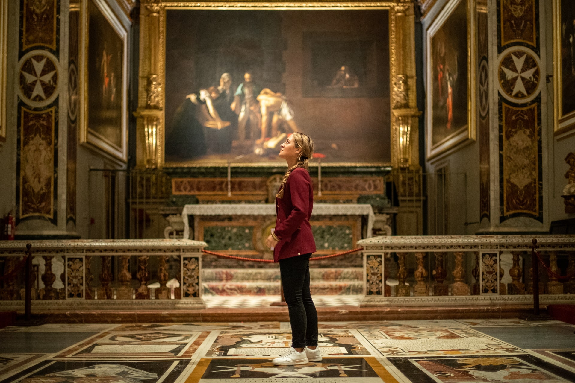 Innenansicht einer Kirche mit Marmorfußboden, Goldverzierungen und Altarbild im Hintergrund