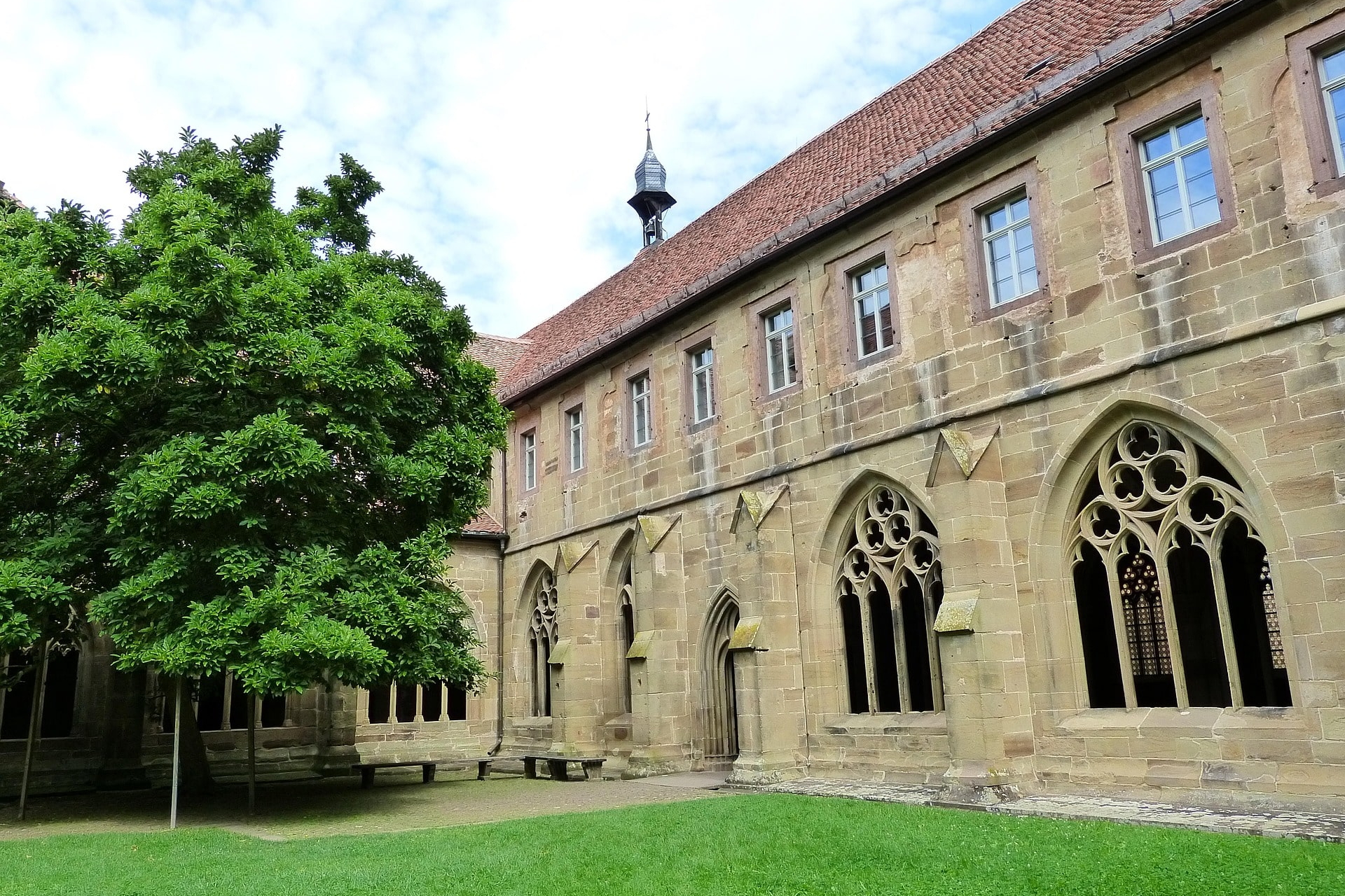 Grüner Innenhof mit gotischen Fenstern und Arkaden