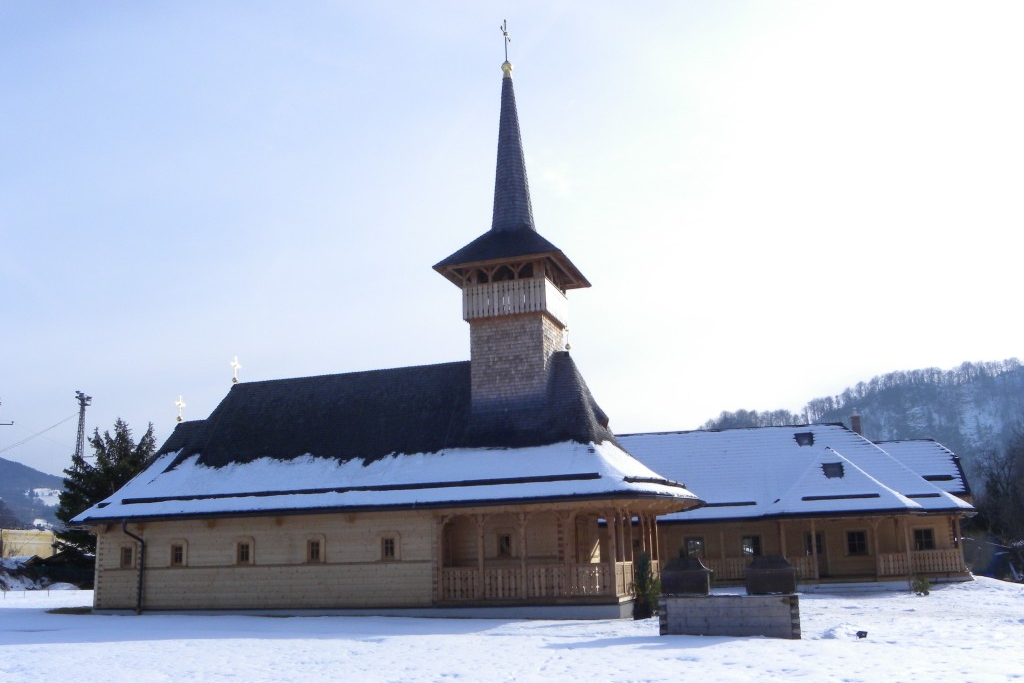 Traditionelle Holzkirche mit hohem Turm im verschneiten Umfeld