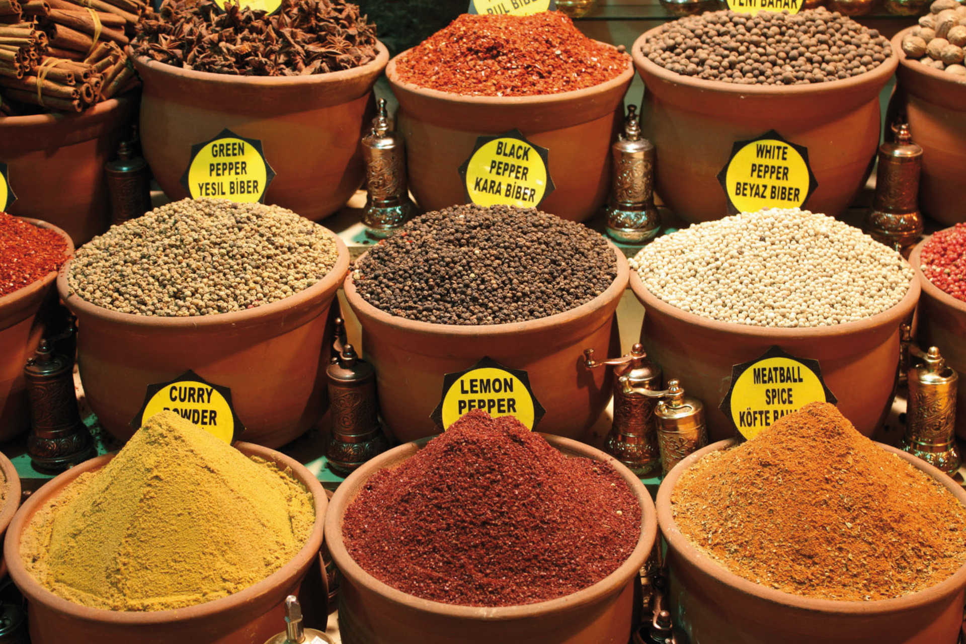 Bunte Gewürzpyramiden in Tonkrügen mit englisch-türkischen Schildern auf dem Gewürzbasar in Istanbul