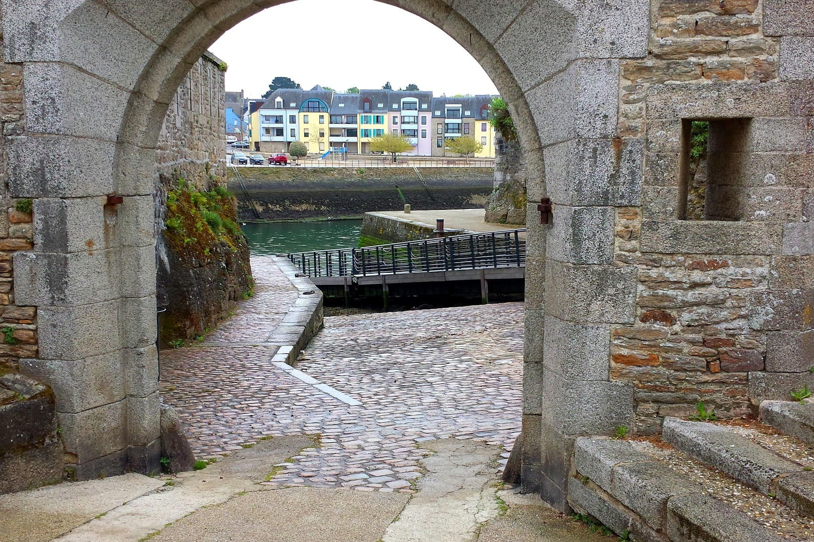 Steinerner Torbogen öffnet Blick auf gepflasterten Weg und Wasserbecken