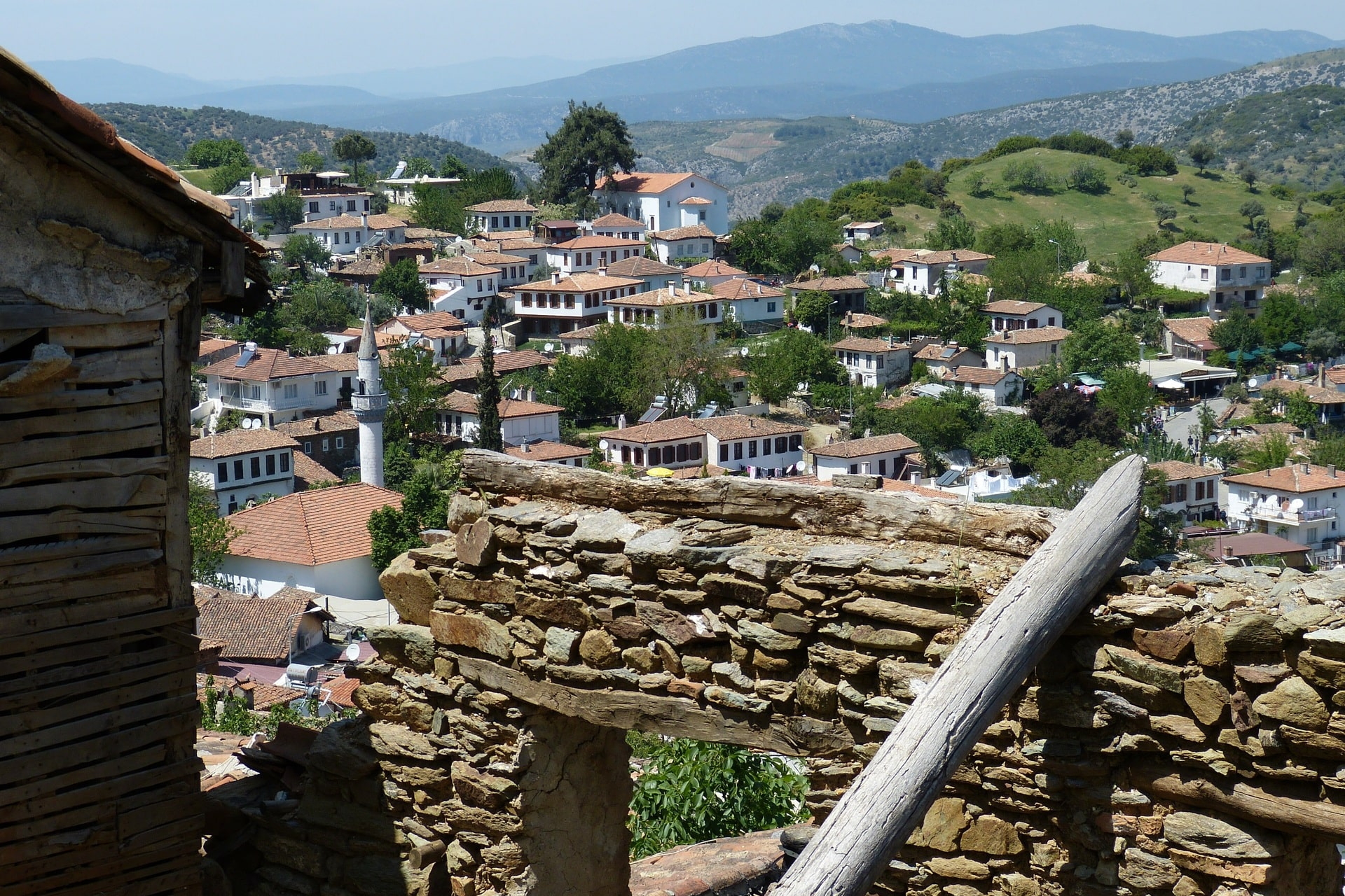 Weiß getünchte Häuser mit roten Dächern zwischen grünen Hügeln