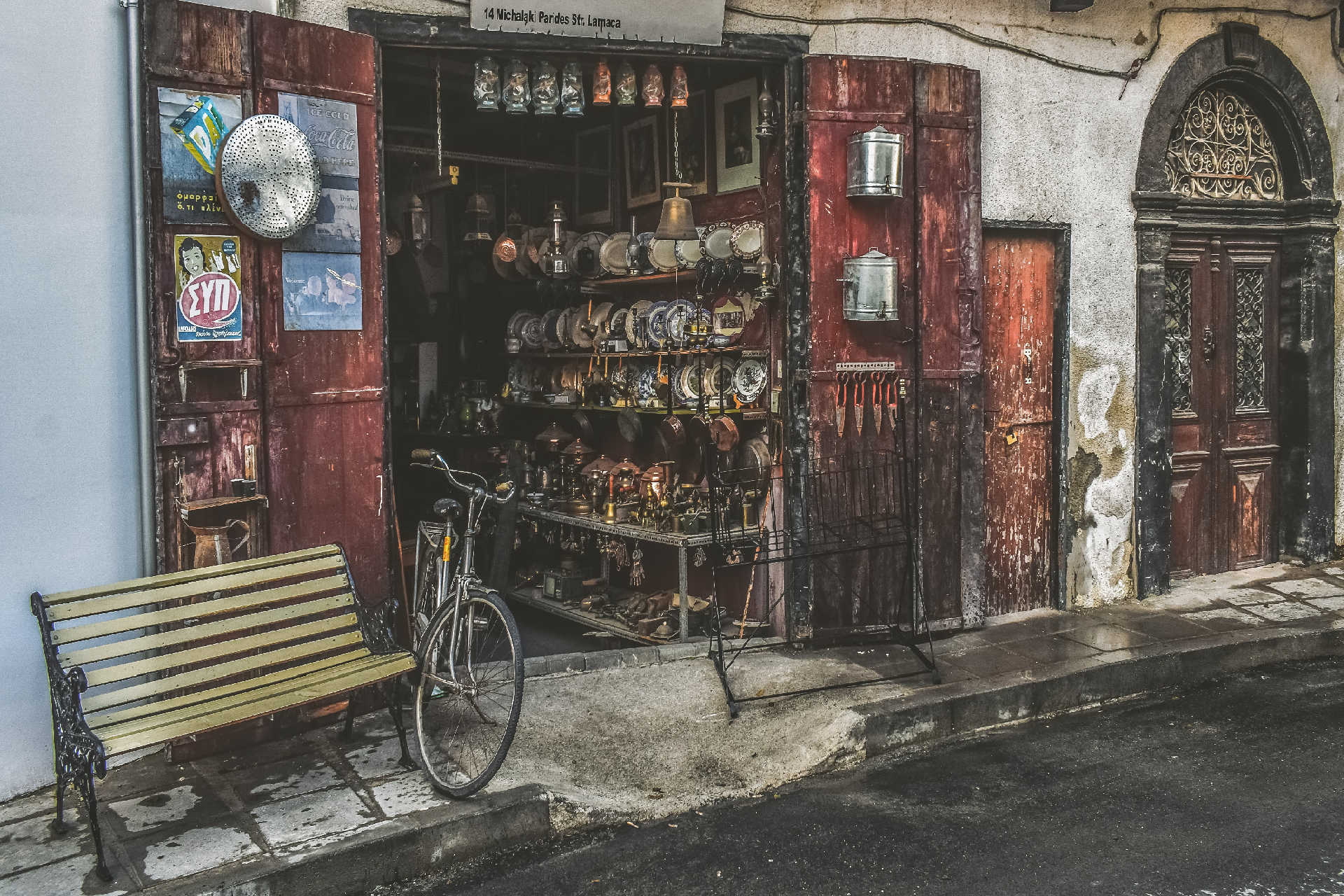Offenes Geschäft mit alten Haushaltswaren, Fahrrad und Bank in Larnaka