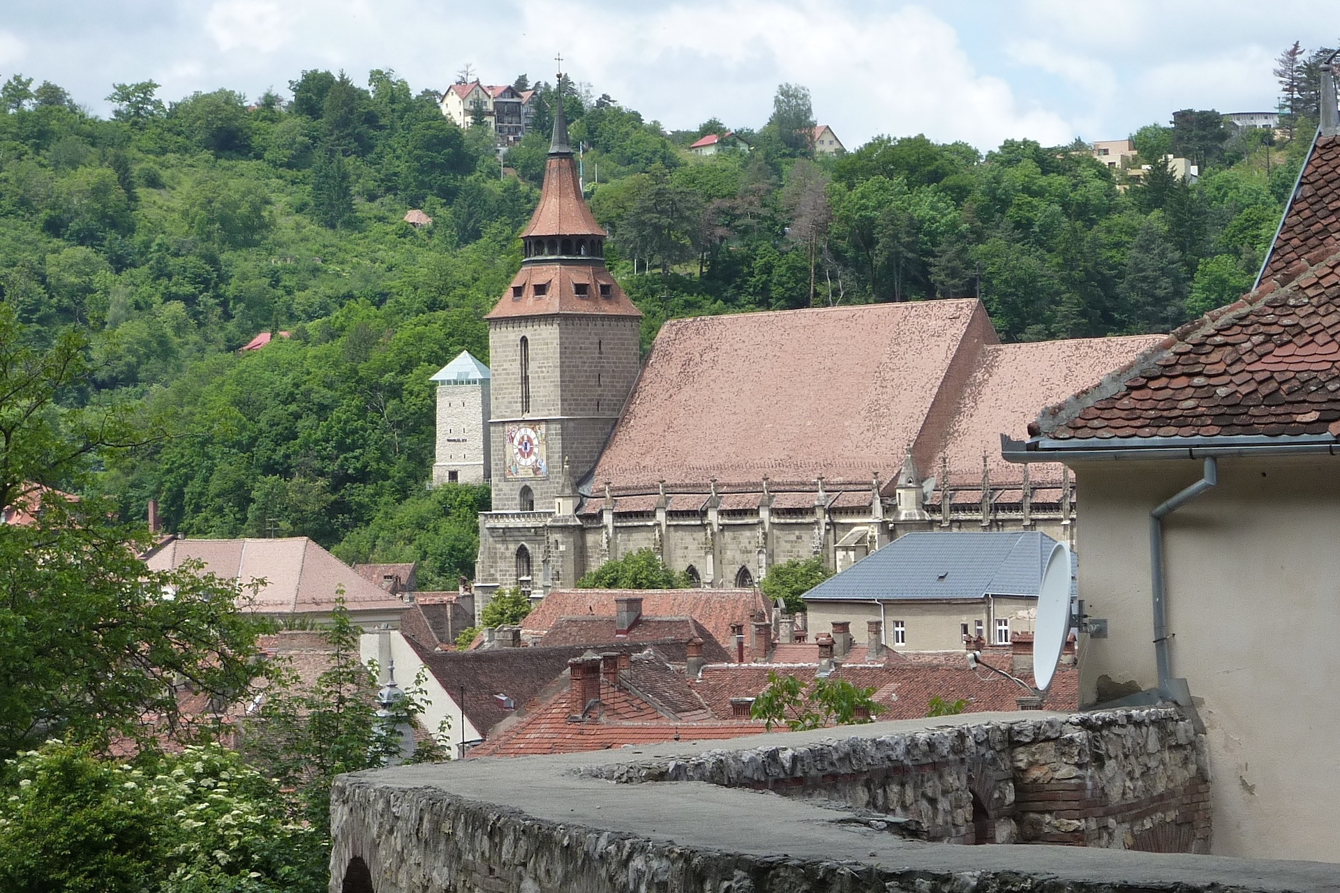 Gotische Schwarze Kirche mit hohem Turm vor bewaldetem Hügel