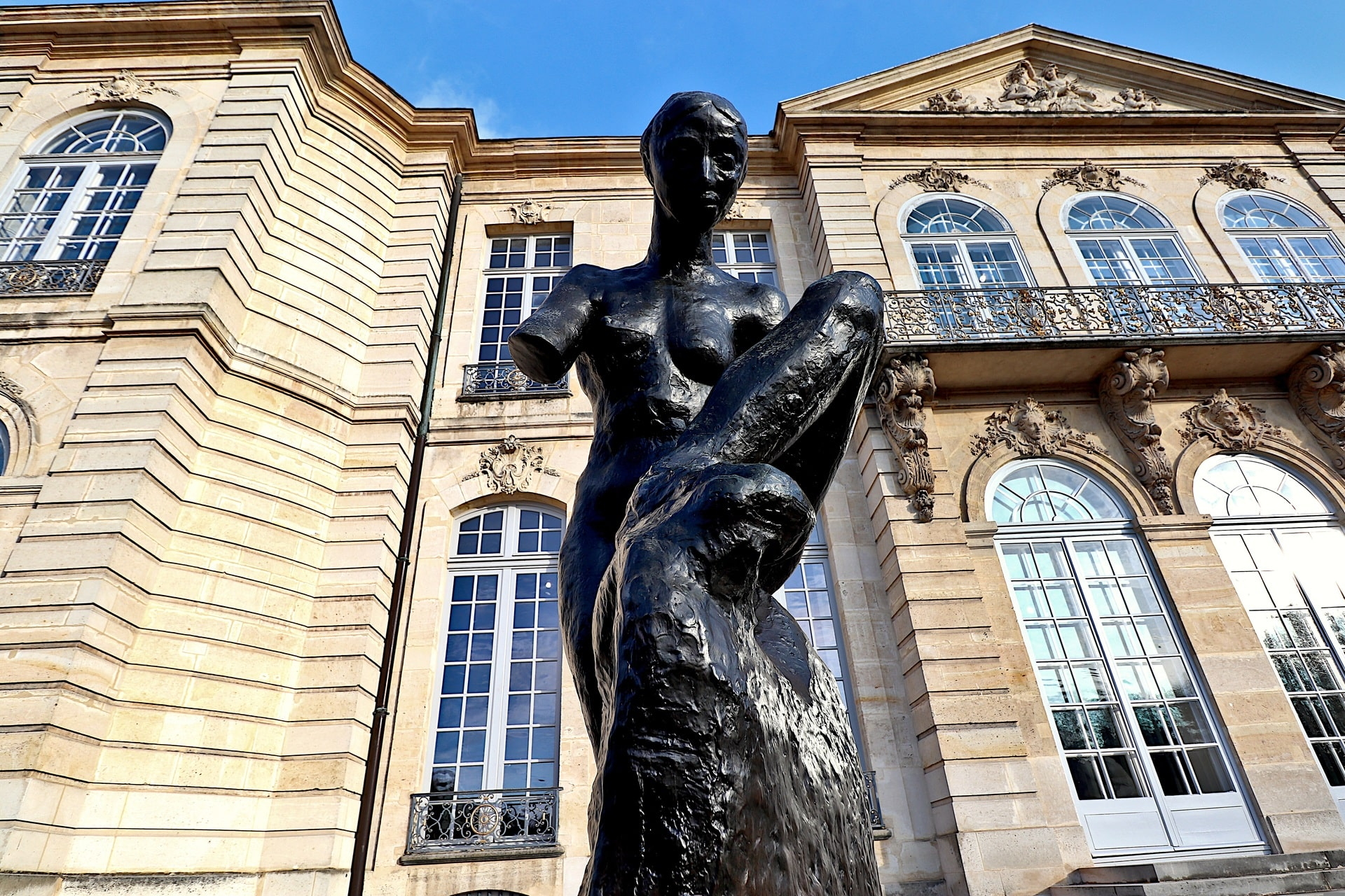 Dunkle Bronzeplastik vor klassizistischem Gebäude