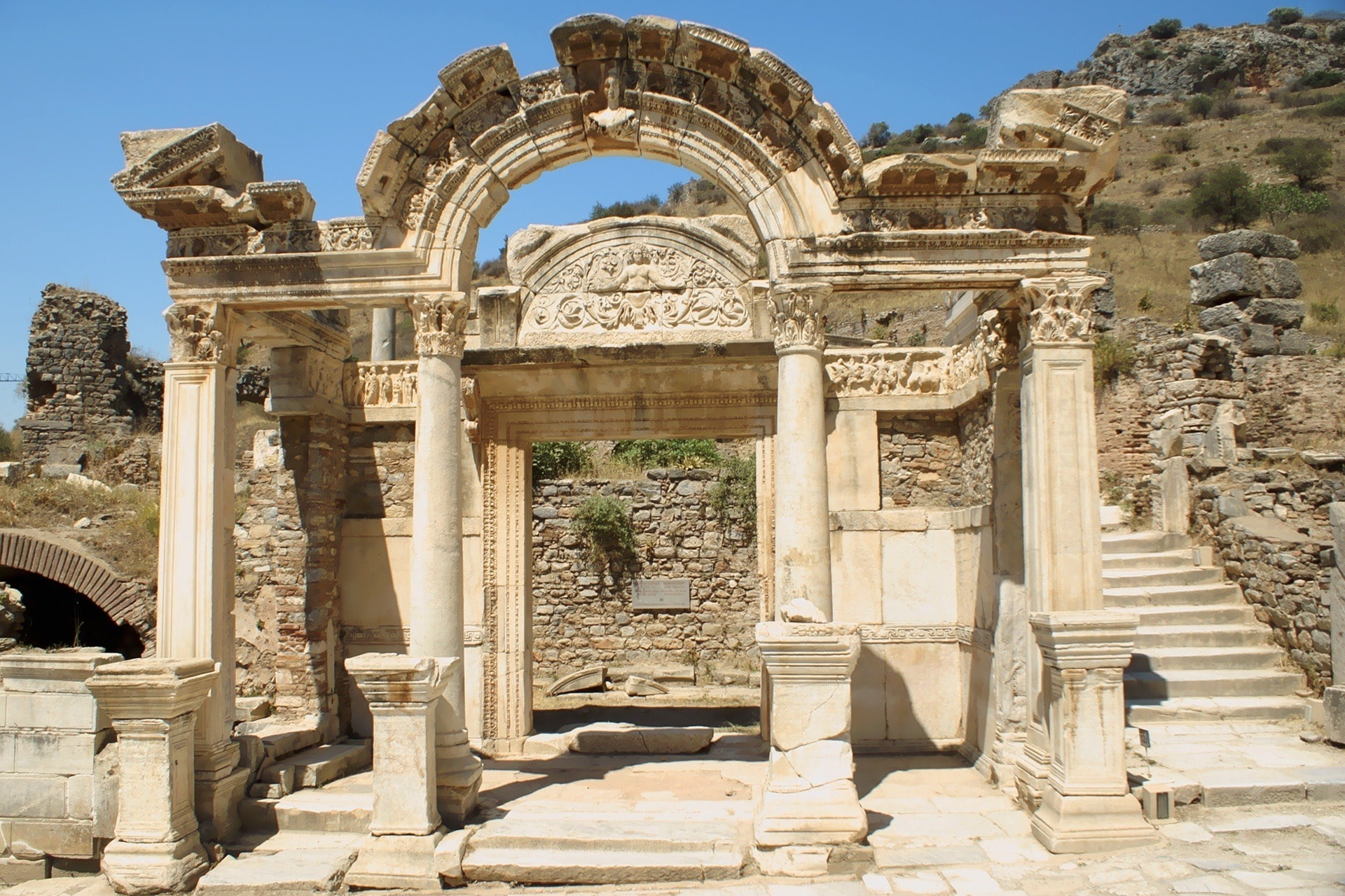 Antiker Tempel mit verziertem Bogen und Marmorsäulen in Ruinenstadt