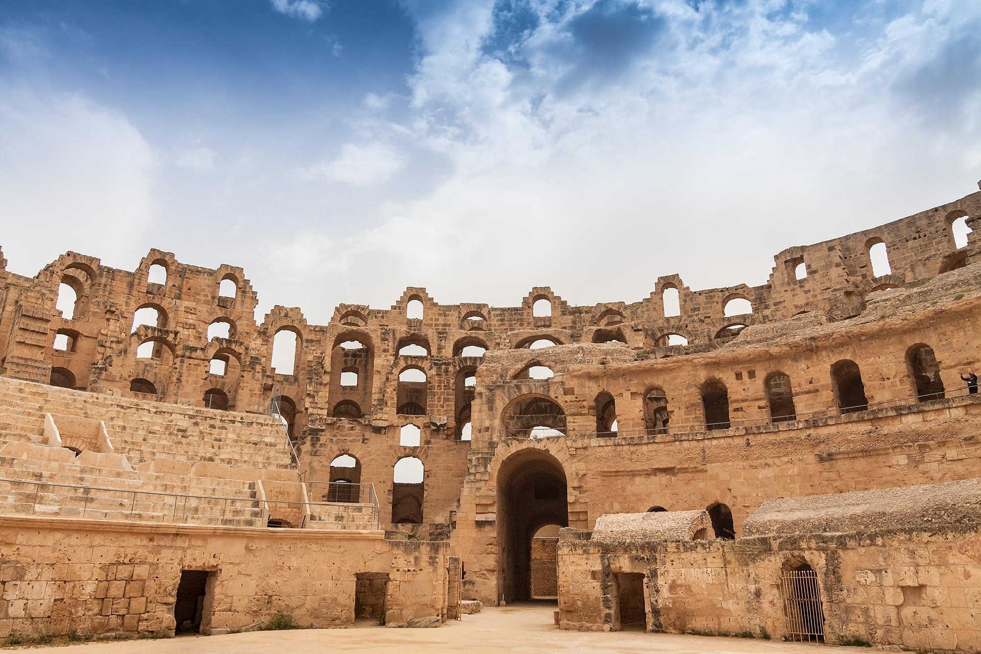 Innenraum der römischen Ruine mit Tribünen und Rundbögen unter Wolkenhimmel