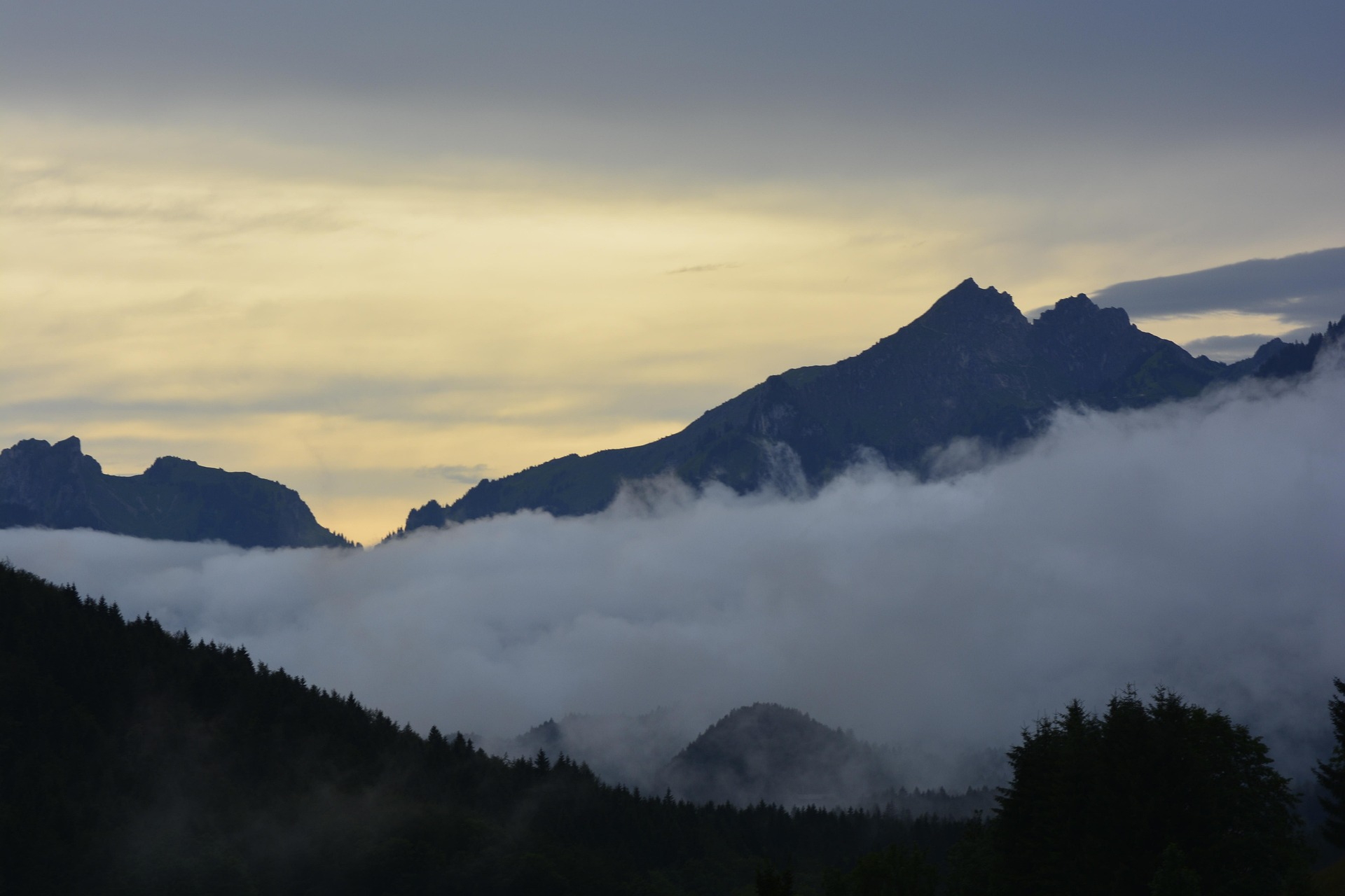 Dunkle Berge mit Wolken und Nebel im Abendlicht