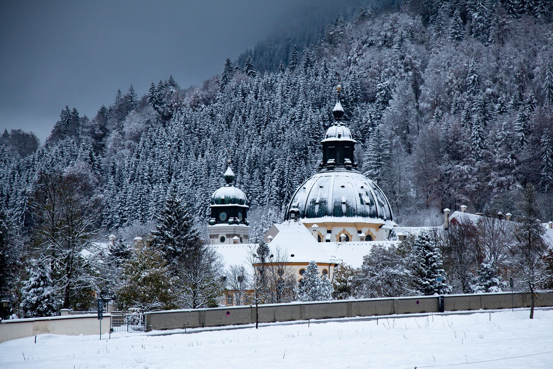 Verschneite Klosterkuppel vor dichtem Nadelwald