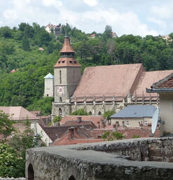 Gotische Schwarze Kirche mit hohem Turm vor bewaldetem Hügel