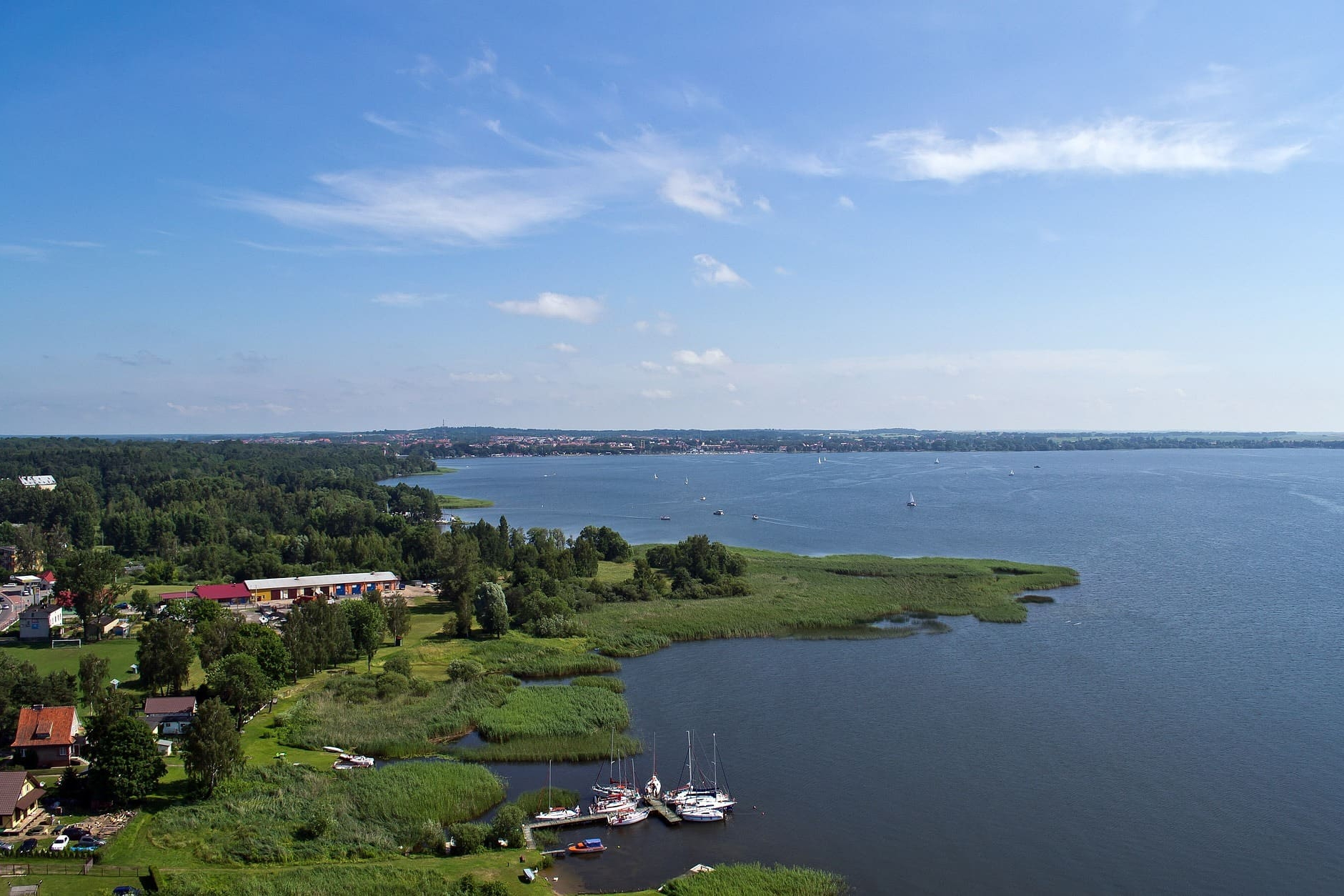 Weitläufige Seenlandschaft mit Booten, Schilf und grüner Umgebung in Polen