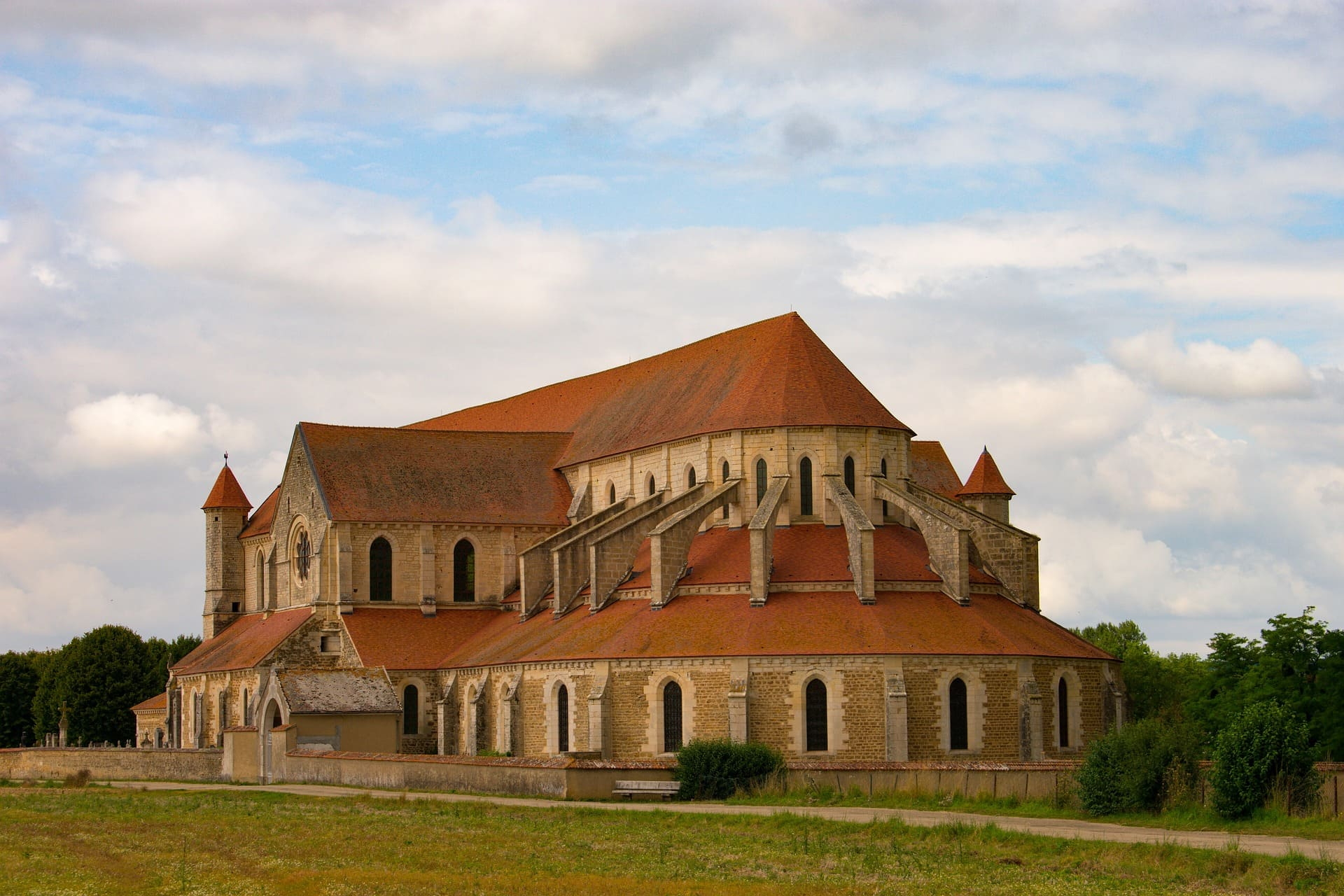 Romanische Klosterkirche mit roten Dächern und Strebepfeilern im Feld