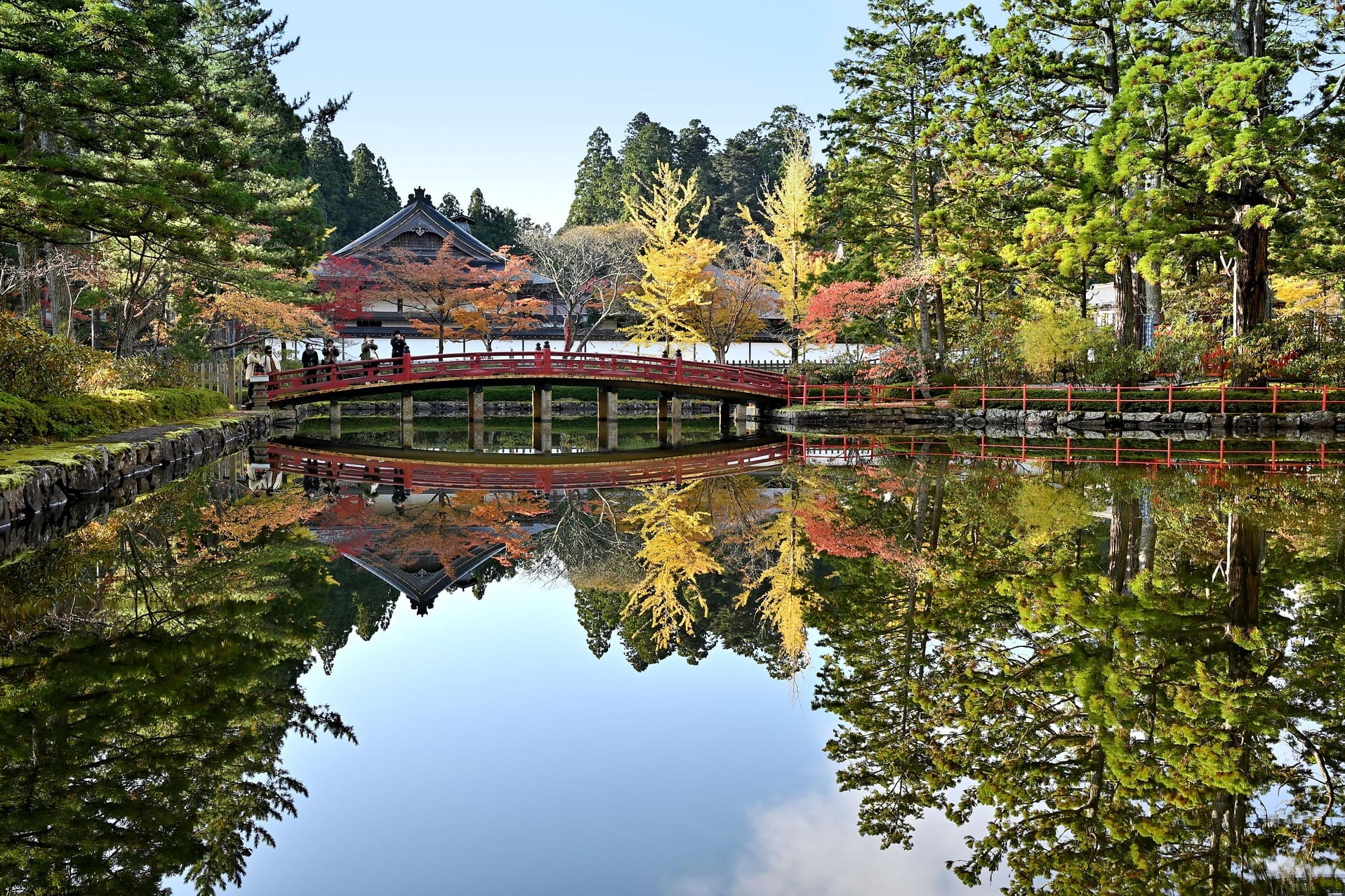 Rote Brücke und Tempel spiegeln sich im klaren Wasserteich