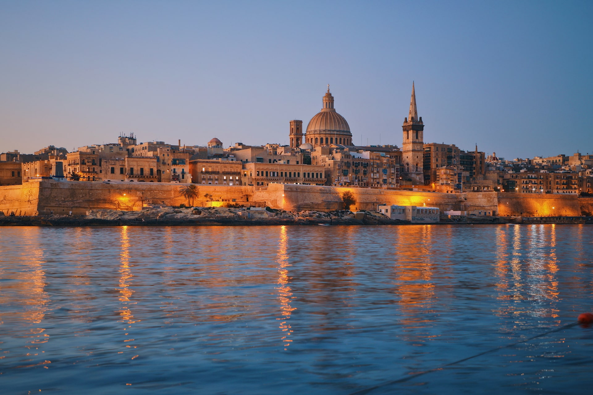 Blick auf die Altstadt von Valletta auf Malta mit beleuchteter Kuppel und Kirchturm zur blauen Stunde