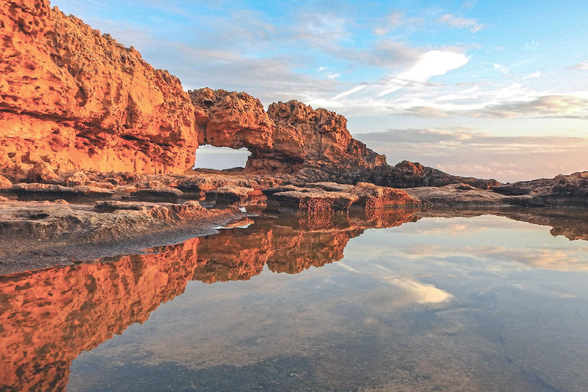 Natürliches Felsentor mit Spiegelung im Wasser bei Sonnenuntergang auf Zypern