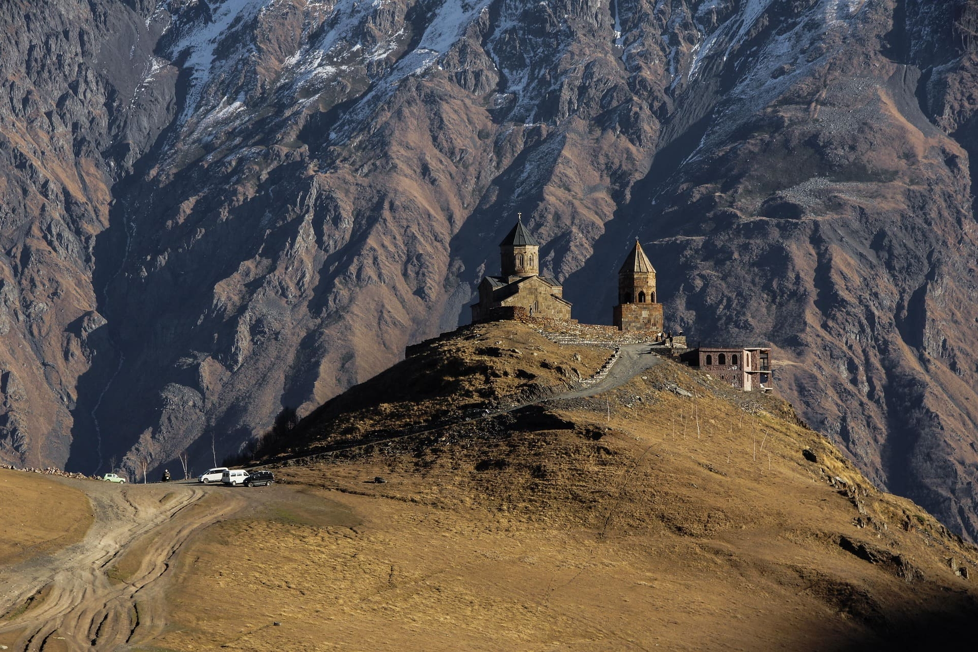 Steinkirche auf Bergkuppe vor schroffen Felswänden