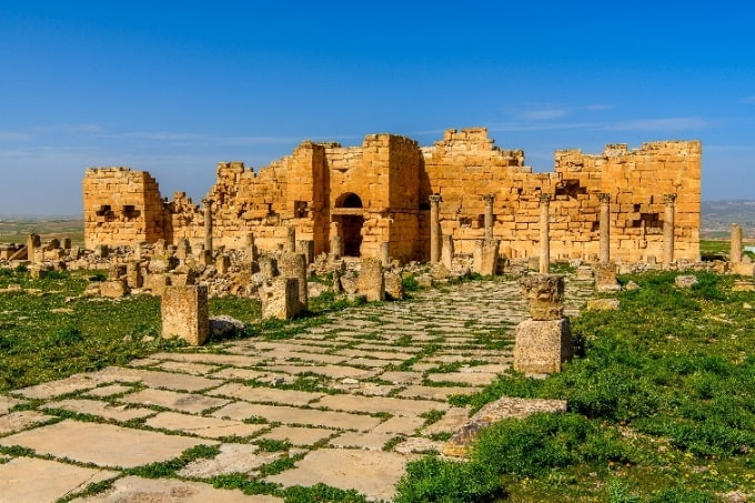 Antike Tempelruine mit Säulen und Steinweg unter blauem Himmel