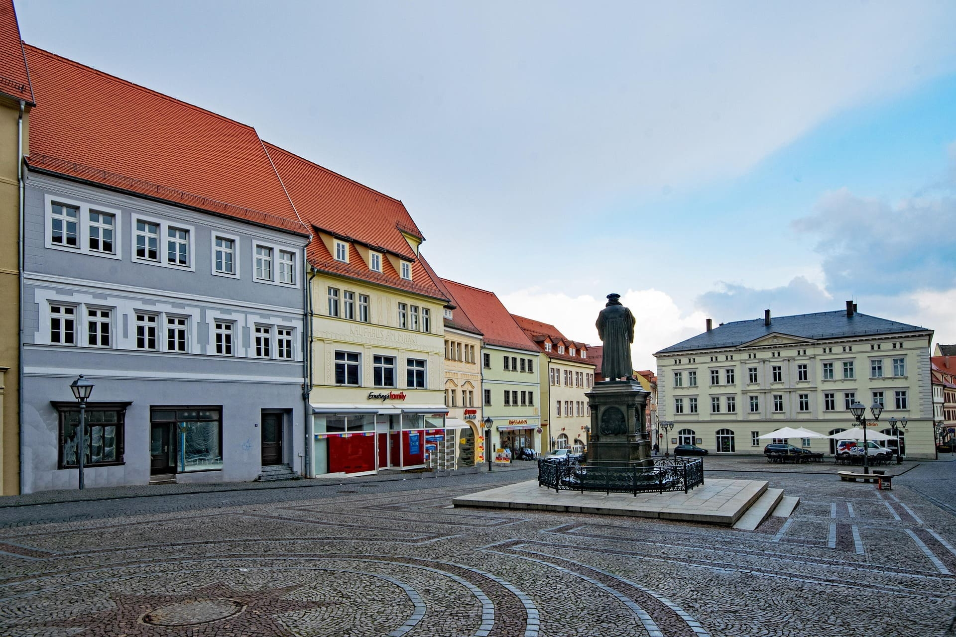 Gepflasterter Platz mit Statue und bunten Fassaden historischer Häuser