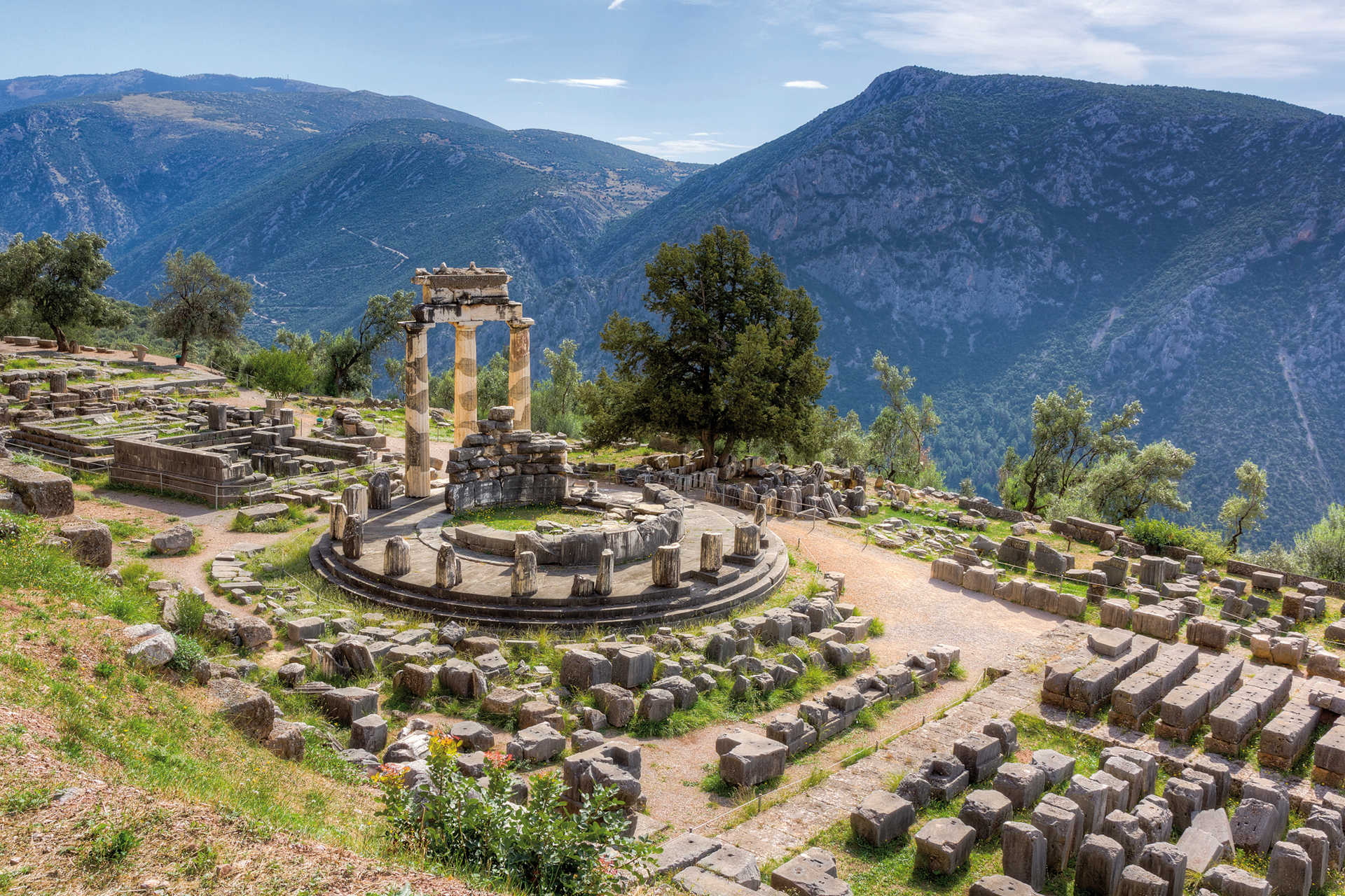 Ruinen des Tholos von Delphi mit umliegender Berglandschaft und antiken Steinen