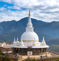Buddhistischer Stupa mit goldenen Details vor grüner Berglandschaft