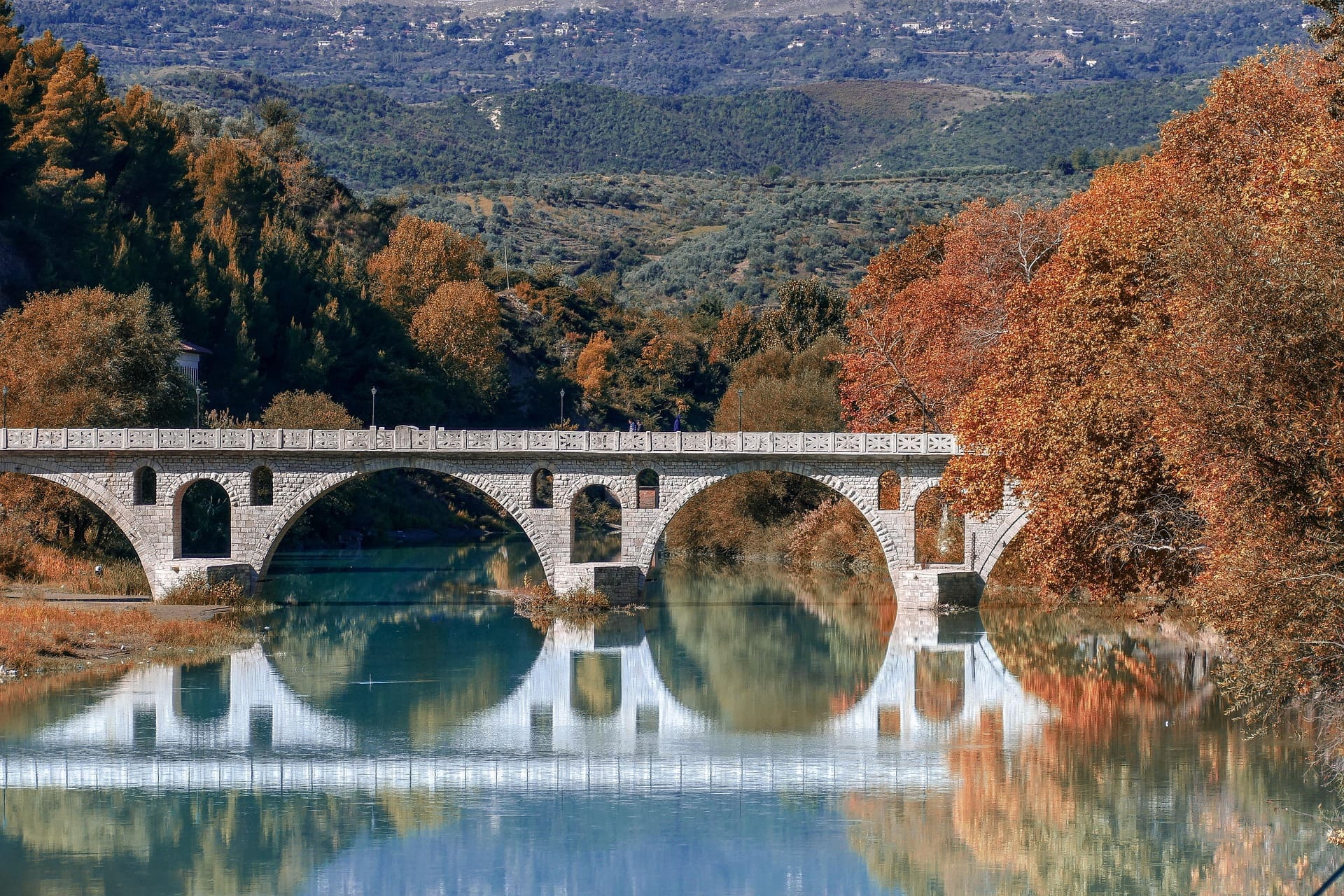 Bogenbrücke spiegelt sich im ruhigen Wasser des Flusses