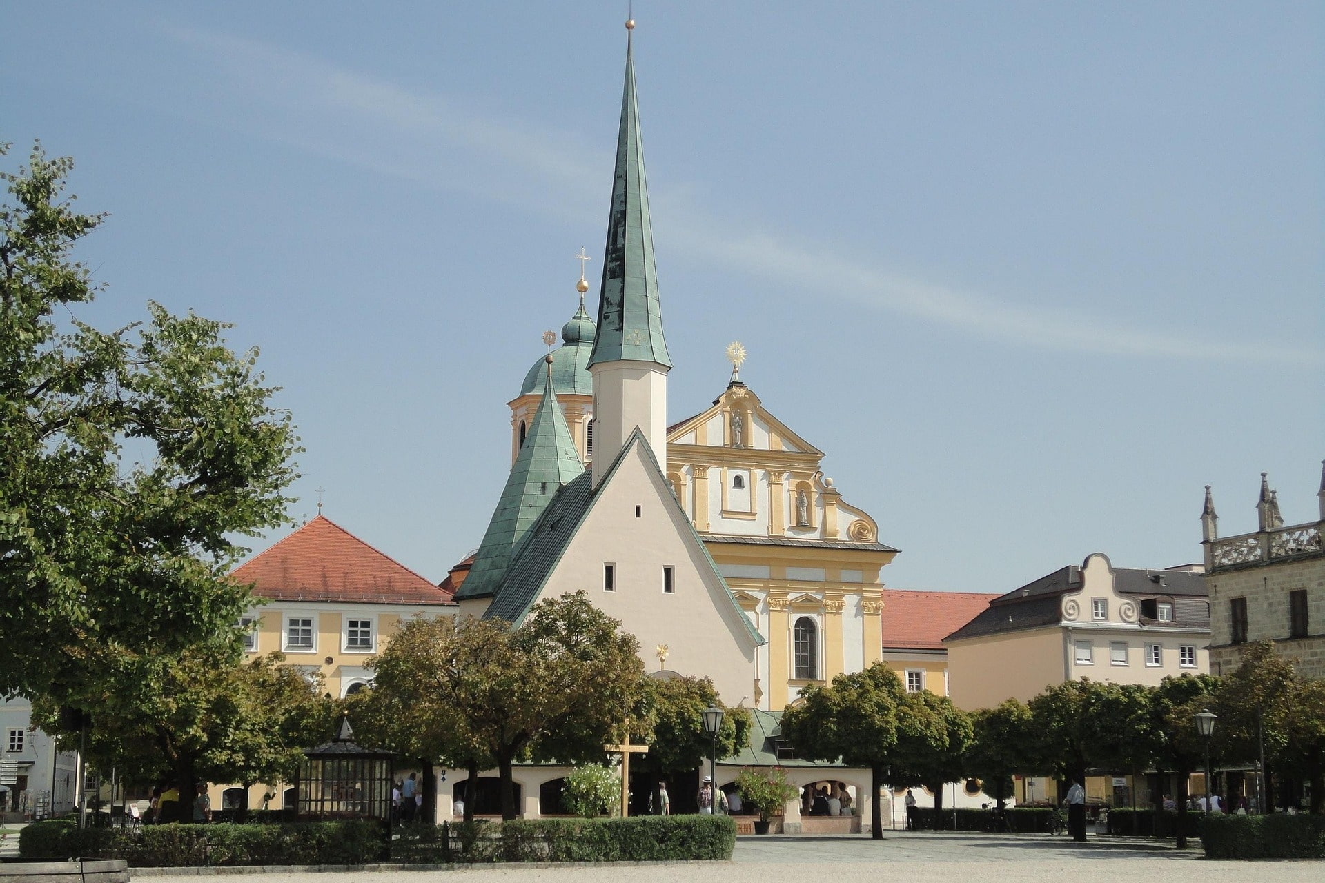 Stadtplatz mit Bäumen und Kirche mit spitzem Turm
