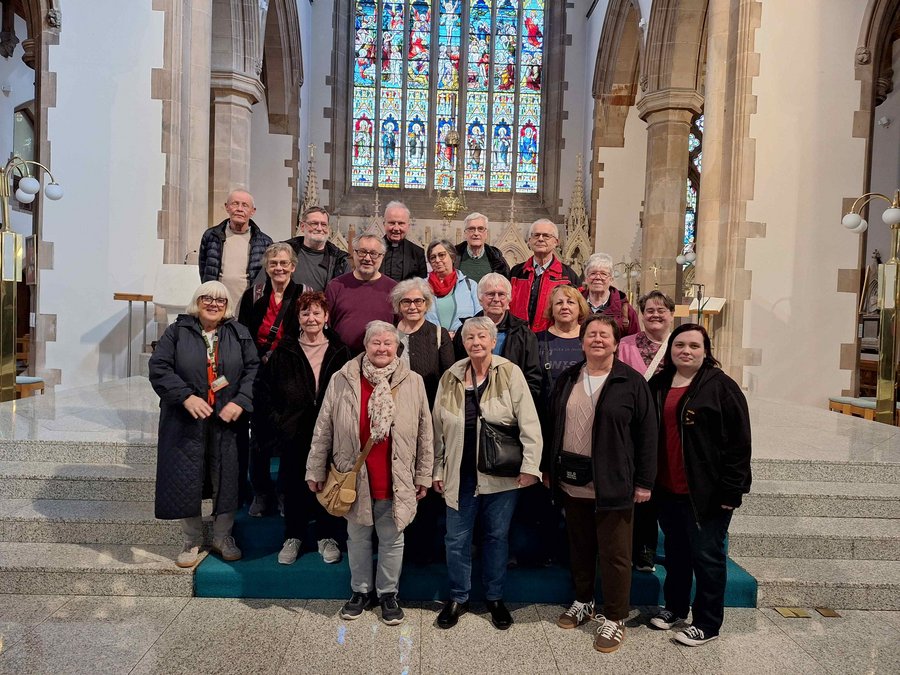 Teilnehmergruppe der Irlandreise in der anglikanischen Kathedrale von Cork mit buntem Glasfenster im Hintergrund