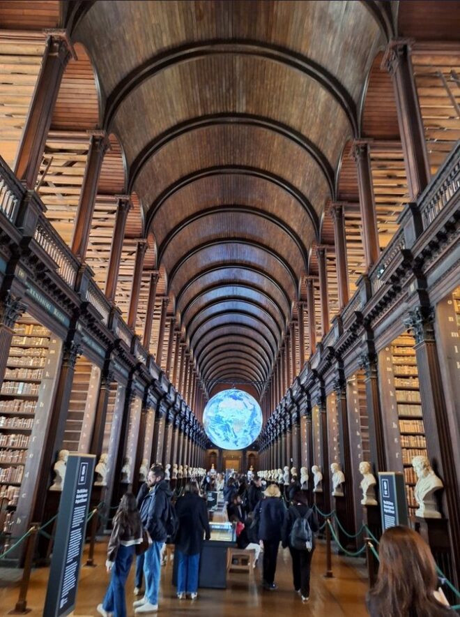 Historischer Lesesaal mit Tonnengewölbe, Holzregalen und Besuchenden in der Trinity College Library in Dublin