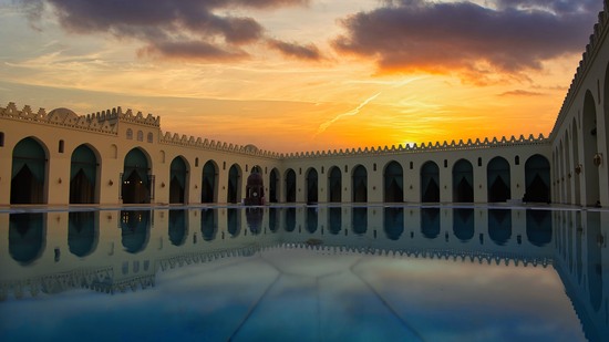Großer Hof mit Arkaden spiegelt sich im Wasser bei Abenddämmerung