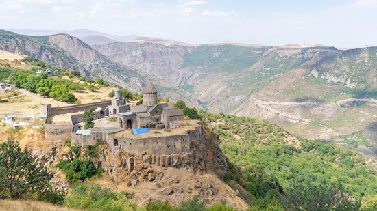 Altes Kloster thront hoch über grünem Tal in Berglandschaft