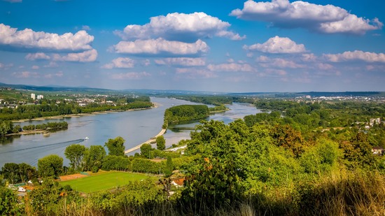 Weiter Fluss mit grünen Inseln und Feldern unter blauem Himmel
