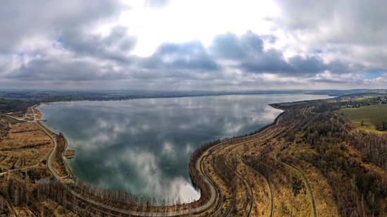 Weiter Fluss mit grünen Inseln und Feldern unter blauem Himmel
