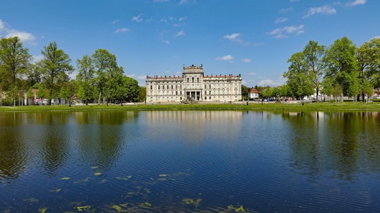 Prächtiges Schloss spiegelt sich im Wasser vor grünem Park