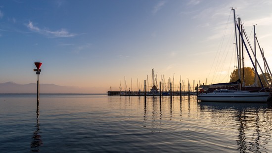 Segelboote im ruhigen Hafen bei Sonnenuntergang am Seeufer