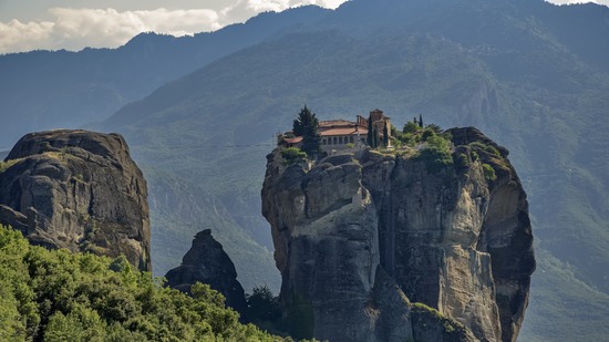 Kloster thront hoch oben auf steilem Felsen vor Bergkulisse