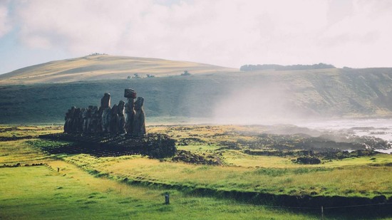 Reihe von Moai-Statuen erhebt sich auf grüner Küstenlandschaft