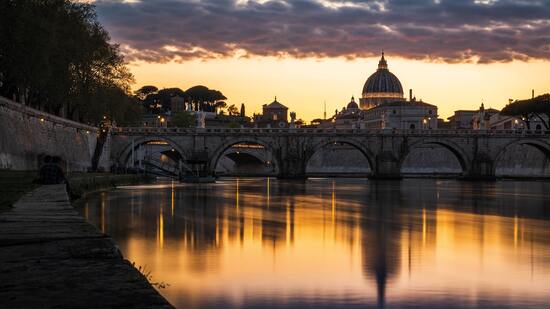 Beleuchtete Brücke spiegelt sich im Fluss mit Kuppel im Hintergrund