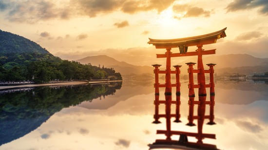 Rotes Torii spiegelt sich im stillen Wasser bei Sonnenuntergang