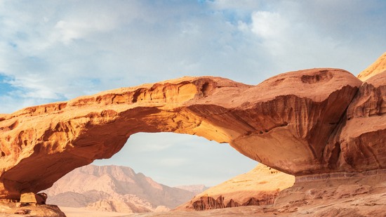 Großer Steinbogen spannt sich über Wüstenlandschaft im Sonnenlicht