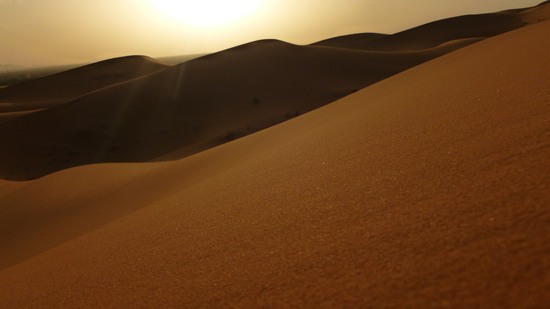 Goldene Sanddünen leuchten im Abendlicht unter tiefstehender Sonne