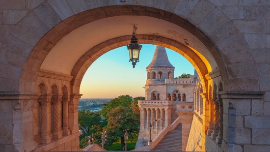Blick durch Steinbogen auf die Türme der Fischerbastei im Abendlicht