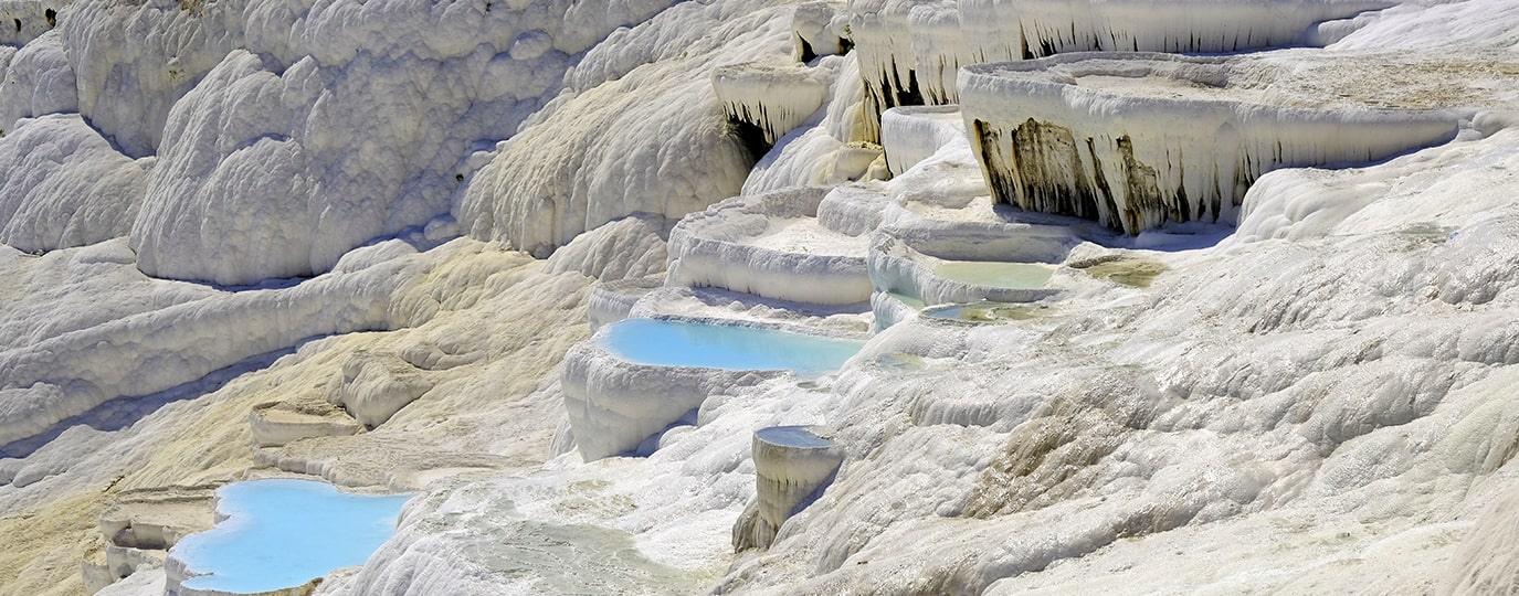 Weiße Kalksinterterrassen mit türkisblauen Wasserbecken